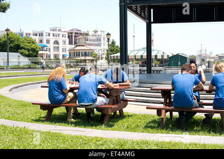 Junge Menschen versammelten sich um Picknicktische entlang Mississippi Fluss im French Quarter von New Orleans Louisiana Stockfoto