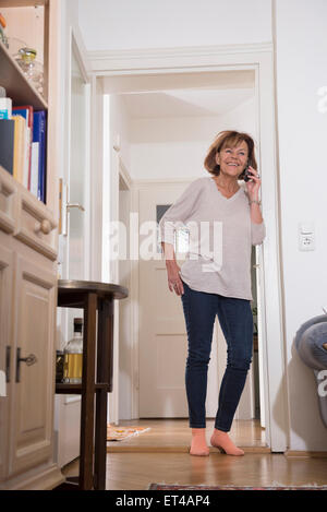 Ältere Frau am Handy an Tür, München, Bayern, Deutschland Stockfoto