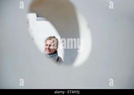 Junge Frau gesehen durch ein rundes Loch in die Betonwand Bayern München Stockfoto