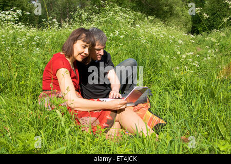 Paar junger Mann und Frau mit Computer Notebook sitzen auf Rasen Wiese. Stockfoto