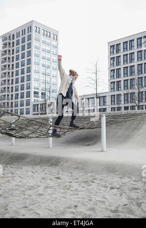 Junge Frau zu Fuß auf Netz in Spielplatz München Bayern Deutschland Stockfoto