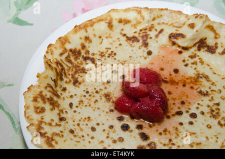 Pfannkuchen Sie mit Erdbeeren Marmelade auf einem Teller an einem Tisch Stockfoto