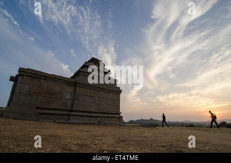 Touristische Wanderungen vor Sonne zwischen Tempel bei Sonnenuntergang in der antiken Stadt Hampi Stockfoto