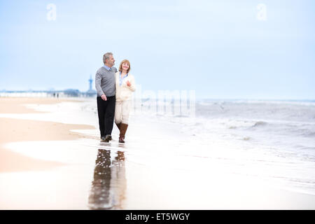 Glücklich im Alter von Mitte Liebespaar zu Fuß auf einem schönen Strand in Holland Stockfoto