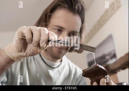 Tischler Anwendung Kleber auf einen antiken Holzstuhl im Workshop, Bayern, Deutschland Stockfoto