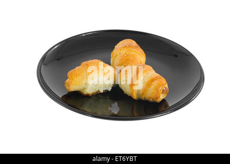 Drei kleine Croissants auf einem schwarzen Teller. Stockfoto