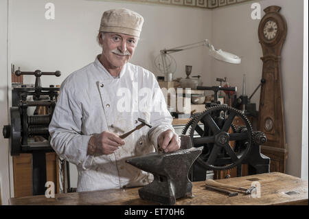 Senior Handwerker Gestaltung der Kupferring am Workshop, Bayern, Deutschland Stockfoto