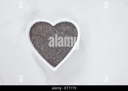 Chia-Samen. Rohe ganze Chia-Samen in einer Schale Herz geformt. Natürliches Licht Stockfoto