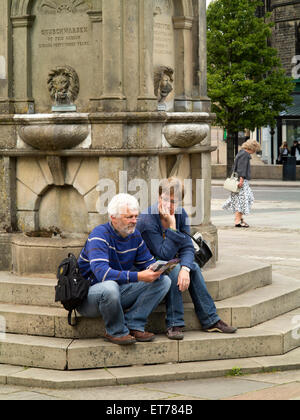 Großbritannien, England, Derbyshire, Buxton, The Crescent, paar saß auf Samuel Turner Memorial Trinkbrunnen Schritte Stockfoto