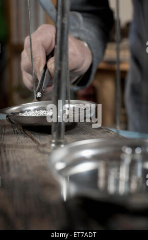 Senior männlichen Goldschmied prüfen Silvers auf Skala am Workshop, Bayern, Deutschland Stockfoto