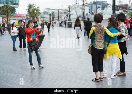 Japanische Touristen fotografieren in London mit Kameras, Handys und Selfie-sticks Stockfoto