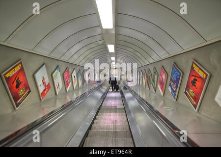 Ein Geschäftsmann nimmt die Rolltreppe hinunter in einem Londoner U-Bahn Rohr Netzwerk, London, UK Stockfoto