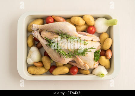 Huhn mit junger Knoblauch, Schalotten, Petersilie, Tomaten, Kartoffeln und Olivenöl in einem Topf braten vorbereitet Stockfoto