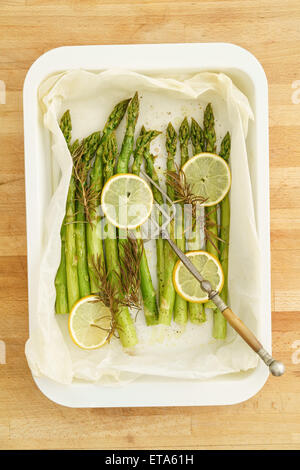 Grüner Spargel mit Zitronenscheiben mit Backpapier in eine Kasserolle gebacken Stockfoto