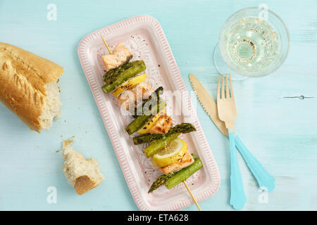 Gegrillter grüner Spargel Spieße mit Lachs, Baguette und Zitronen Stockfoto