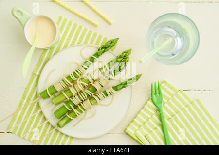 Spieße mit gedünstetem Spargel umwickelt mit Spaghetti mit Sauce Hollandaise Stockfoto