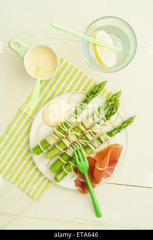 Spieße mit gedünstetem Spargel mit Spaghetti mit Sauce Hollandaise und Schinken umwickelt Stockfoto