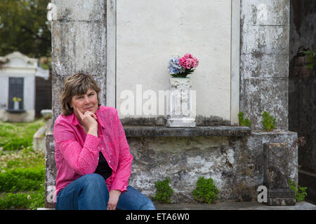 Frau im historischen Friedhof von New Orleans.  Blick in die Kamera.  Kopieren Sie Speicherplatz auf Krypta, wenn nötig.  Trauer und Erinnerung. Stockfoto