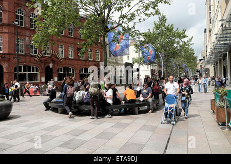 Menschen sitzen muslimische Paar schieben Kind in Kinderwagen auf Stadt Straße im Cardiff City Centre St Davids 2 Einkaufsviertel Fußgängerzone im Juni Sonnenschein Wales Großbritannien KATHY DEWITT Stockfoto
