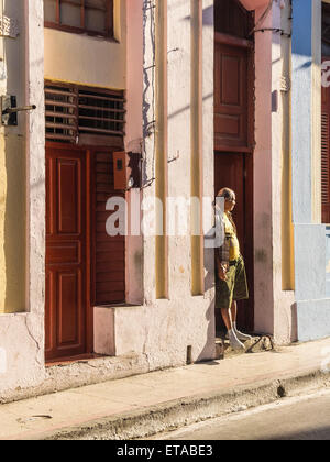 Hispanic Mann stand in den frühen Morgenstunden Licht in Tür öffnen in der Innenstadt von Santiago De Cuba. Stockfoto