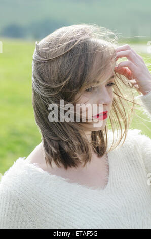 Schöne junge Frau Hand zu berühren, Haare wegschauen Stockfoto