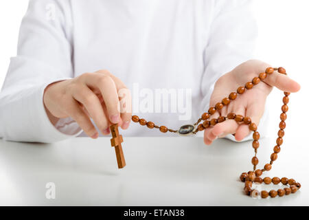 Ein kaukasischen junge mit beiden Händen hält Rosenkranz mit Symbol des Barmherzigen Jesus unter Körner Stockfoto