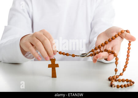 Ein kaukasischen junge mit beiden Händen hält Rosenkranz mit Symbol des Barmherzigen Jesus unter Körner Stockfoto