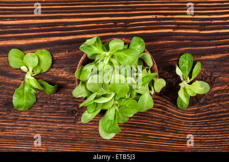 Frisches Grün Feldsalat in Holzschale auf alten hölzernen Vintage-Hintergrund, Ansicht von oben. Frischer Salat, rustikalen Vintage Landhausstil Stockfoto