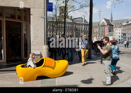 Mann nimmt Bild der Frau in riesigen gelben Clog in Amsterdam auf dem Dam Stockfoto