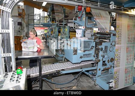 GREYMOUTH, Neuseeland, 22. Mai 2015: Eine unbekannte Frau bündelt sich Zeitungen wie sie gedruckt werden Stockfoto