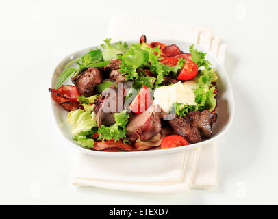 Pfanne gebratene Hühnerleber mit Salat und Speckstreifen Stockfoto