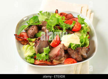 Pfanne gebratene Hühnerleber mit Salat und Speckstreifen Stockfoto