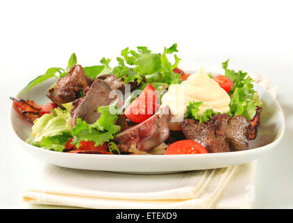 Pfanne gebratene Hühnerleber mit Salat und Speckstreifen Stockfoto