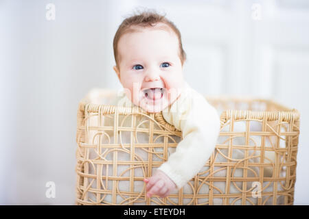 Liebenswert lachendes Baby-sitter in einen Wäschekorb Stockfoto