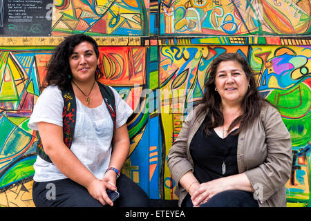 Zwei Frauen vor einer Wand voller Graffiti, Bellavista Nachbarschaft, Santiago, Chile Stockfoto
