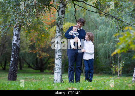 Vater und zwei Kinder, die zu Fuß in einem Wald an einem schönen Herbsttag Stockfoto