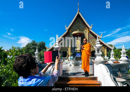 Asien. Thailand, Chiang Mai. Wat Phra Singh. Mönch vor der goldenen Statue eines verehrten Mönchs fotografiert werden. Stockfoto