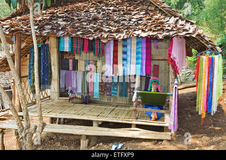 Eine Frau, die das Weben auf der Veranda ihrer Hütte auf dem Hügel Stämme Dorf in der Nähe von Chiang Rai. Stockfoto