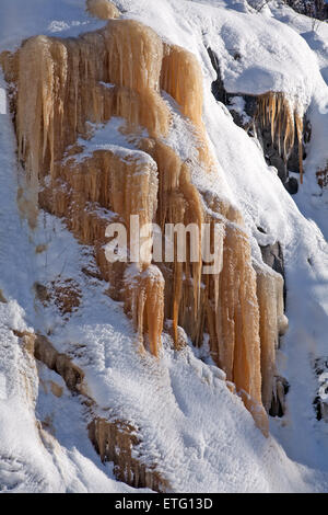 Eisenoxid gefärbt Eiszapfen am Fuße eines Hügels. Stockfoto