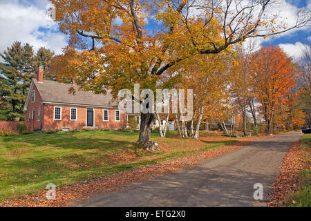 New England aus rotem Backstein Kap-style Home steht neben einem Feldweg im Herbst in Franken, NH, USA. Stockfoto