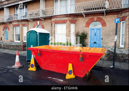 Skip und tragbare Toilette vor einem Haus renovierungsbedürftig, East Anglia England UK Europa zu verweigern. Stockfoto