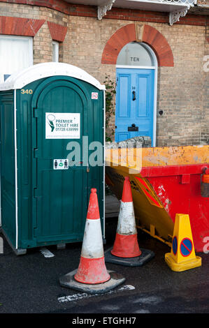 Skip und tragbare Toilette vor einem Haus renovierungsbedürftig, East Angleia England UK Europa zu verweigern Stockfoto