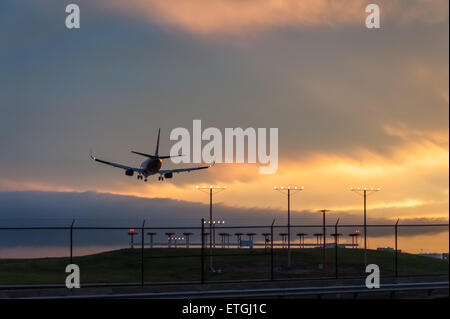Passenger Jet Landung in Atlanta International Airport unter einer feurigen Sonnenuntergang Himmel in Atlanta, Georgia (USA) Stockfoto