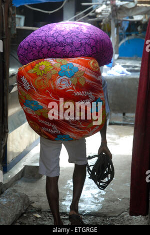 Mann, Sack Wäsche in Mahalaxmi Dhobi Ghat Open-Air Waschsalon, Mumbai, Maharashtra, Indien. Stockfoto