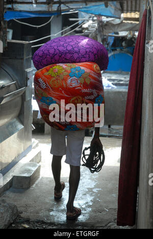 Mann, Sack Wäsche in Mahalaxmi Dhobi Ghat Open-Air Waschsalon, Mumbai, Maharashtra, Indien. Stockfoto