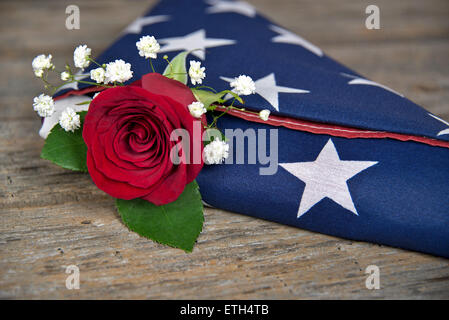 Rote Rose in einem gefalteten amerikanische Flagge auf rustikalen Holz. Stockfoto