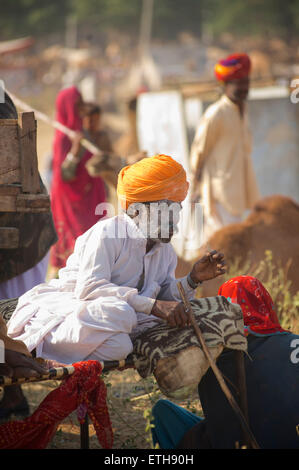 Rajasthani Mann in markanten weißen Kleidung und orange Turban, Rauchen. Pushkar, Rajasthan, Indien Stockfoto