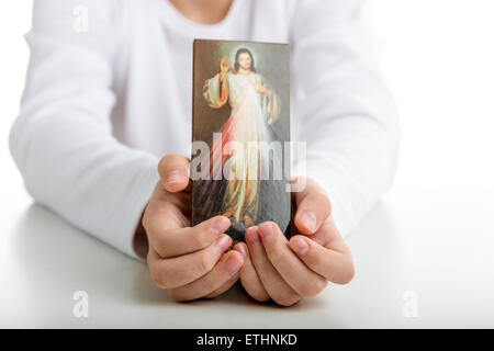 Ein kaukasischen junge zeigt ein Bild des Barmherzigen Jesus hielt es mit beiden Händen Stockfoto