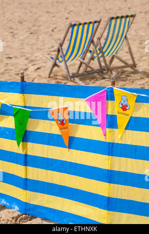 Bookstart Bunting hängen, Windschutz und Liegestühlen am Strand von Bournemouth im Juni Stockfoto