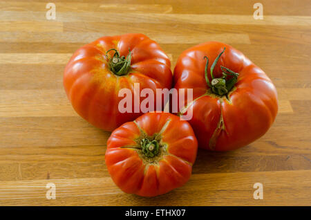 Drei große Fleischtomaten auf einem Holztisch. Stockfoto